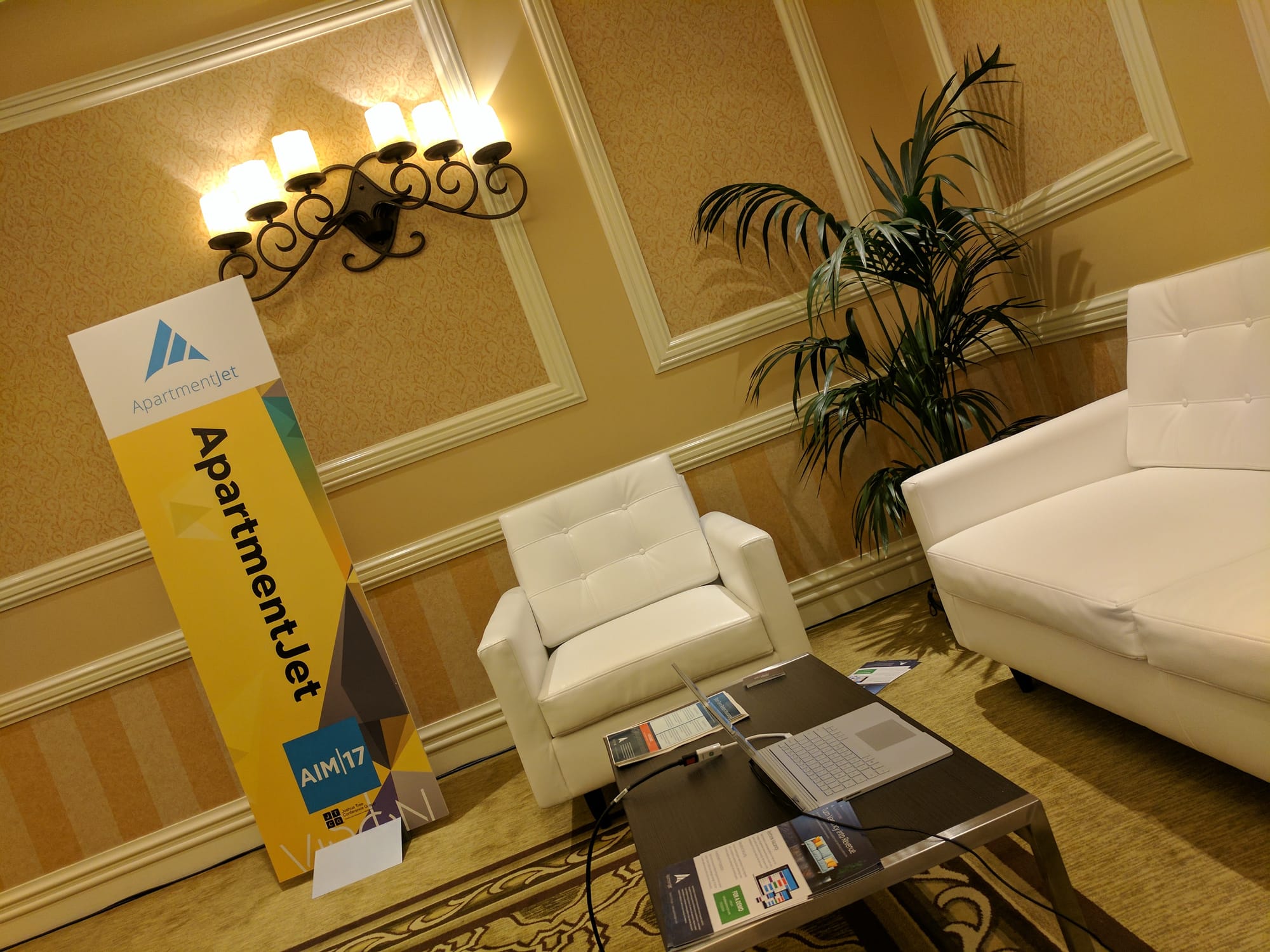 ApartmentJet booth at AIM 2017. Couch, table, sign.
